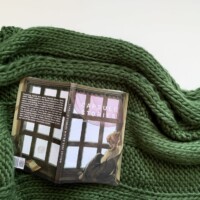 A book laying on a knit green blanket